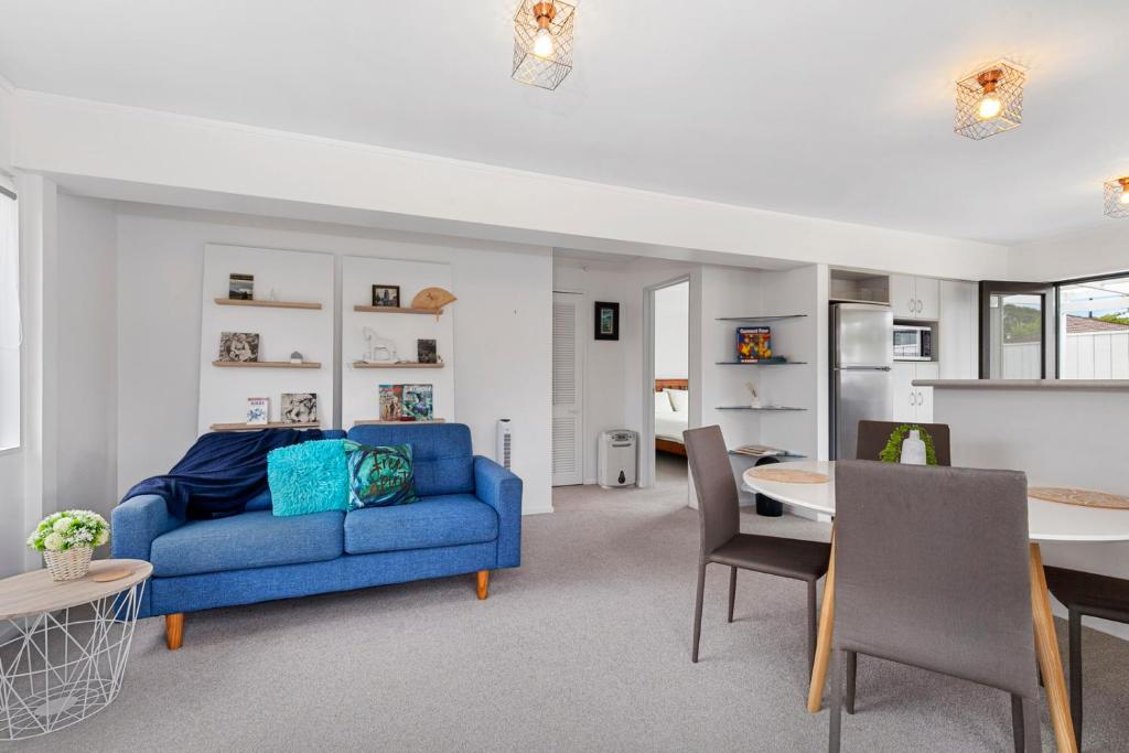 a living room with a blue couch and a table at Orewa Estuary Retreat - Orewa Downstairs Unit in Orewa