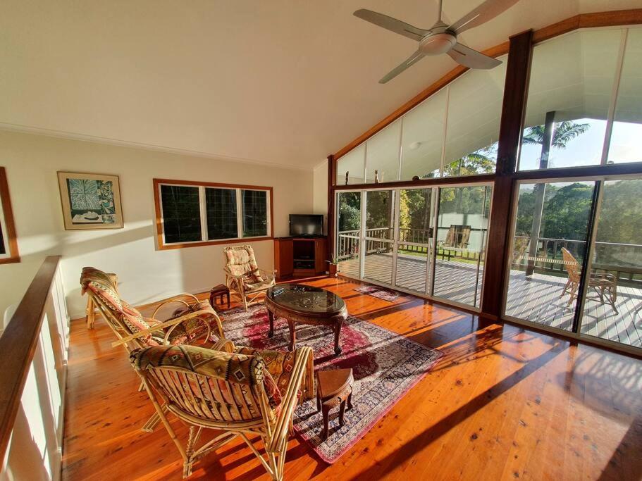 a large living room with a ceiling fan and chairs at Private Rainforest Ridge Retreat in Kuranda