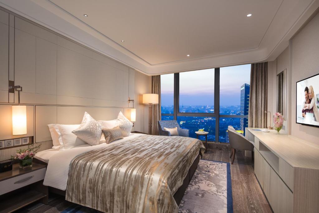 南通市にあるAscott Harmony City Nantongのベッドと大きな窓が備わるホテルルームです。