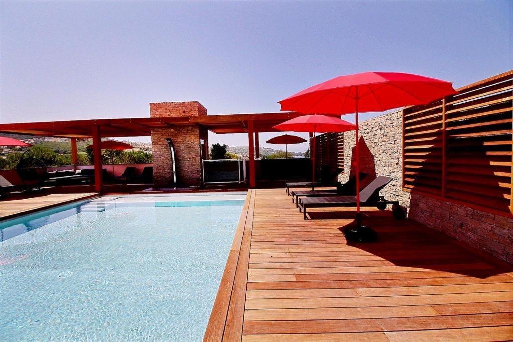 a pool with red umbrellas and chairs and a swimming pool at Residence ACQUA LINDA Porticcio in Porticcio