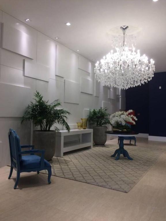 a room with a chandelier and a table and a chair at Ed. Mauí, 2 suítes, divisa Capão e Atlântida in Capão da Canoa