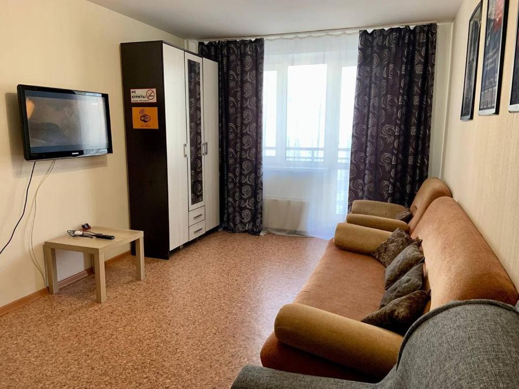 a living room with a couch and a tv at 2к Апартаменты на верхнем этаже на проспекте Ермакова, 10 in Novokuznetsk