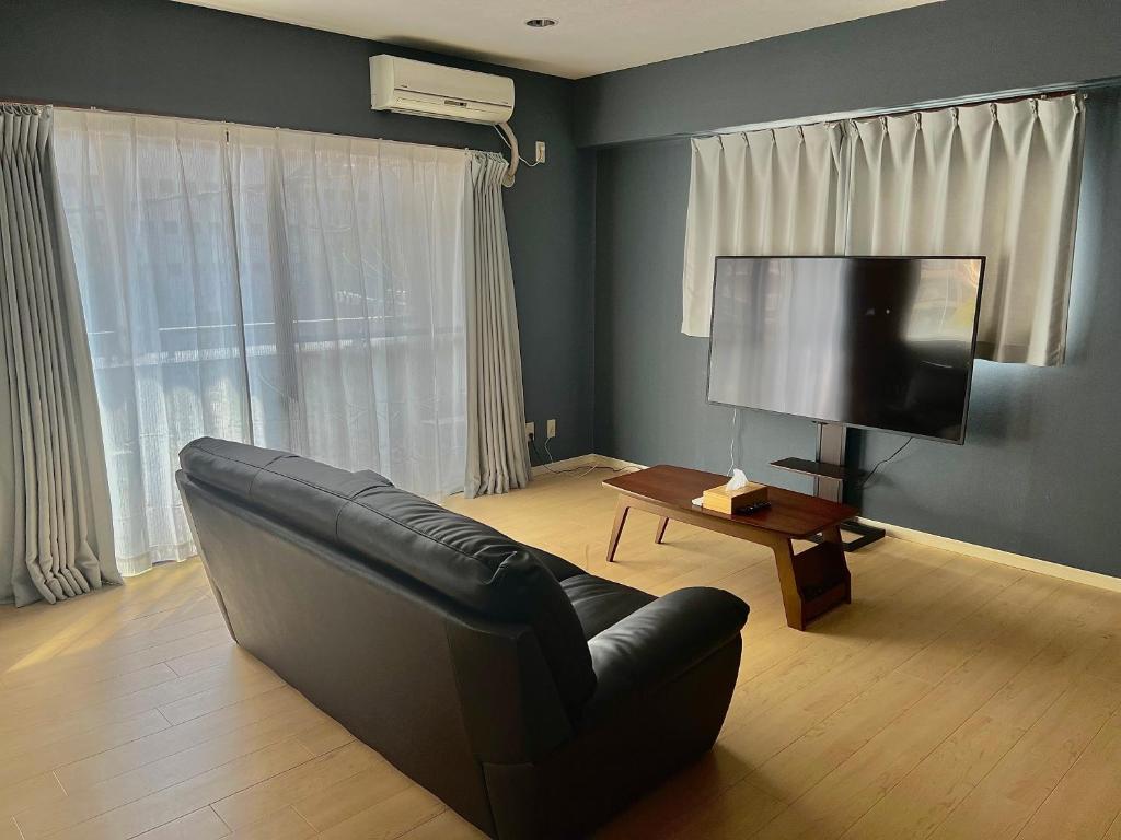 sala de estar con sofá negro y TV en Parkside Inn Hakata No4, en Fukuoka