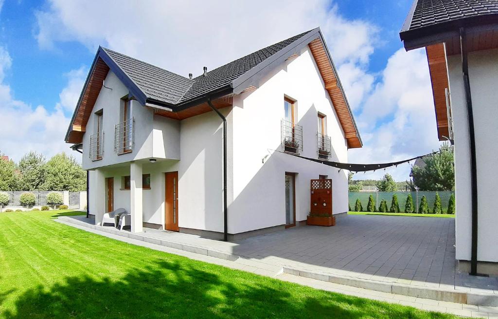 uma pequena casa branca com um jardim verde em BŁĘKIT Apartamenty przy Jastrzebiej em Mieroszyno