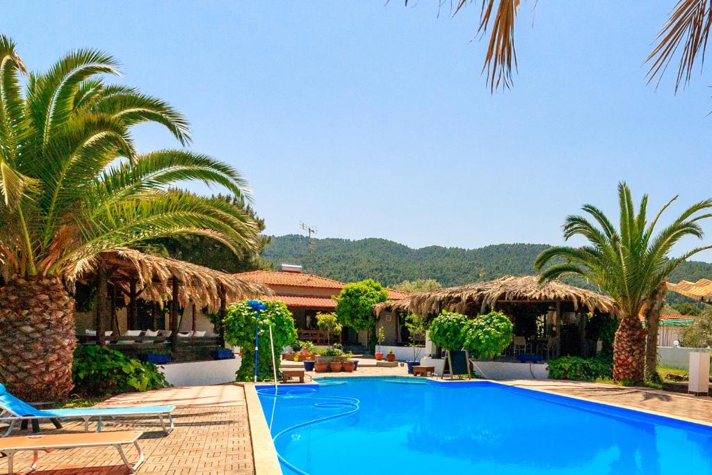 a resort with a swimming pool and palm trees at Kissos Apartments in Vourvourou