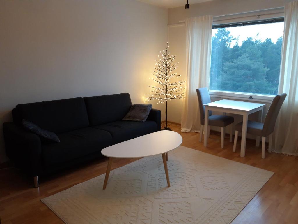 uma sala de estar com um sofá preto e uma mesa em Viihtyisä yksiö Oulun Tuirassa em Oulu