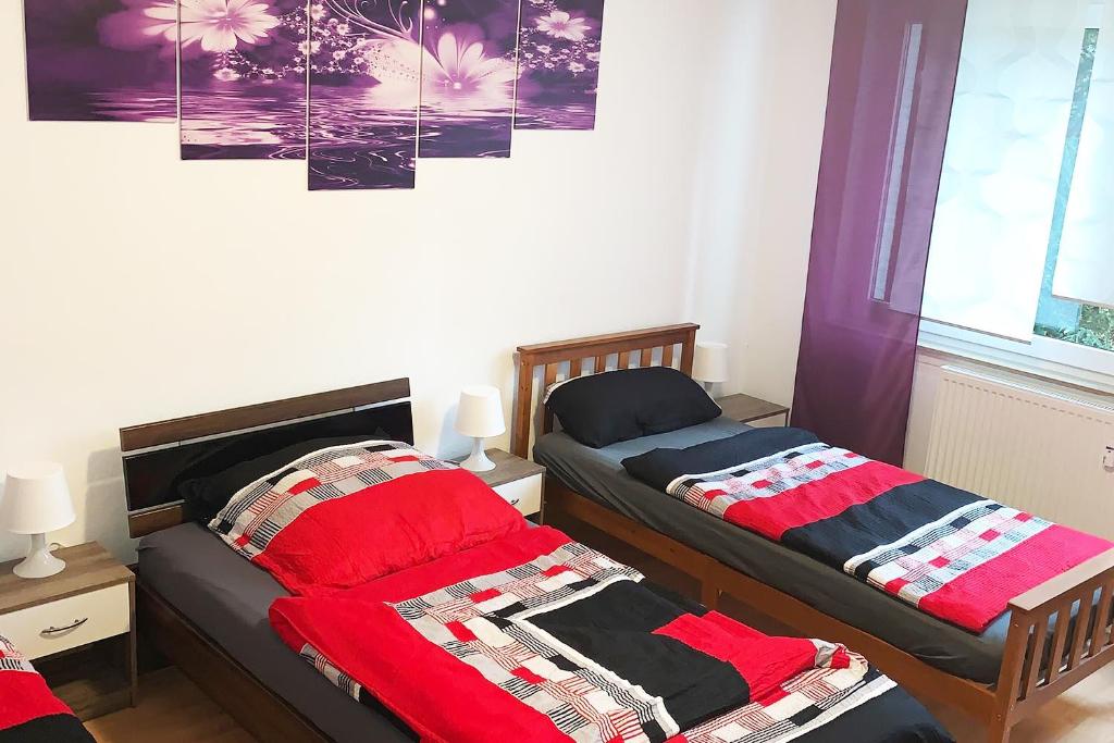 a bedroom with two beds with red blankets and a window at 3 room holiday flat in Hemer