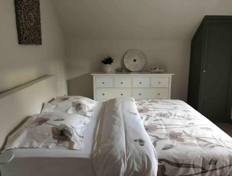un letto con lenzuola bianche e un comò in una camera da letto di 'T Achterhuys a Ostenda
