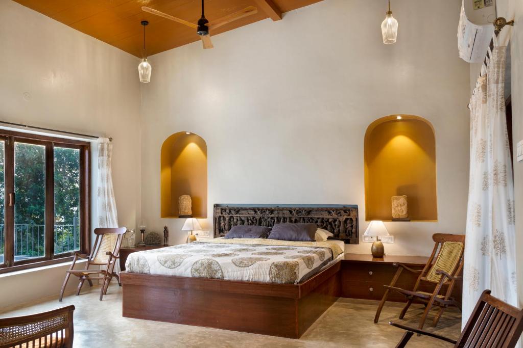 a bedroom with a large bed in a room with chairs at Private Terrace Room with the most scenic views in Alibaug