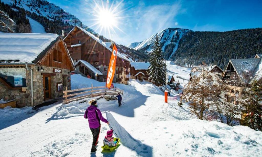 a woman and child on skis in the snow near a lodge at Les Rousses in Oz