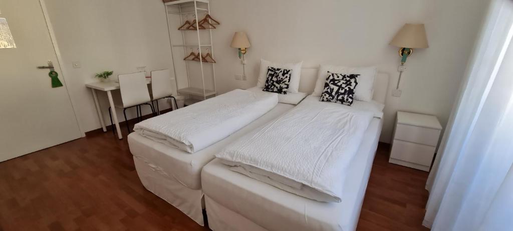 a bedroom with two beds with white sheets at Hotel Corona in Locarno