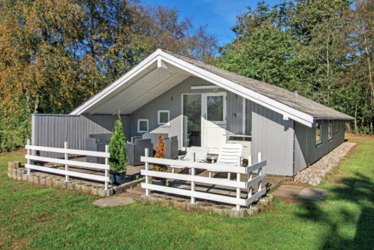 a gray shed with a white fence in front of it at Holiday Home M&A in Toftlund