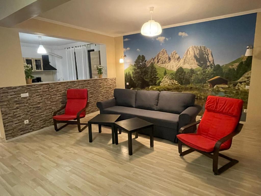 ブシュテニにあるApartament Holiday Busteniのリビングルーム(ソファ、赤い椅子2脚付)