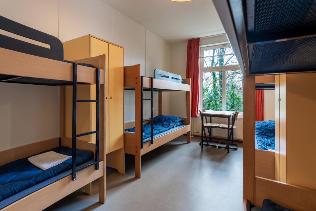 een kamer met een stapelbed, een bureau en een raam bij Stayokay Hostel Arnhem in Arnhem