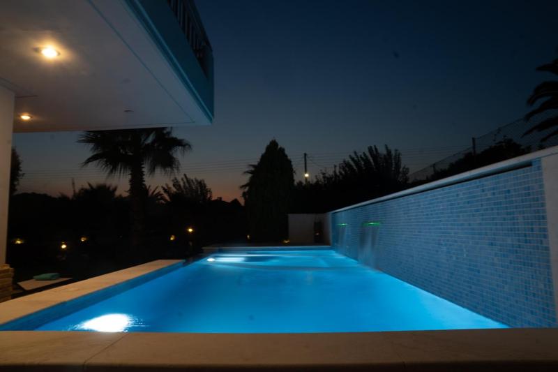 ein nachts beleuchteter Pool in einem Haus in der Unterkunft Luxury heated pool Villa in Lagonisi