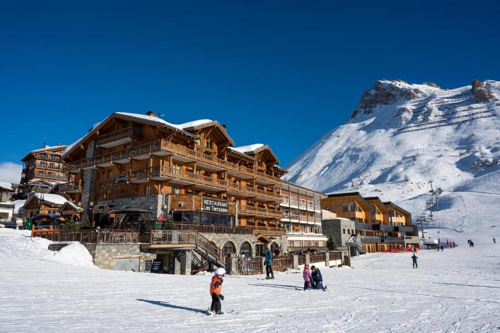 蒂涅的住宿－Hôtel Le Levanna by Les Etincelles，雪地里的人在滑雪场上的滑雪小屋