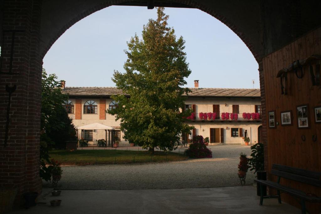 ein Torbogen mit einem Baum vor einem Gebäude in der Unterkunft Agriturismo Cascina Nuova in Barge