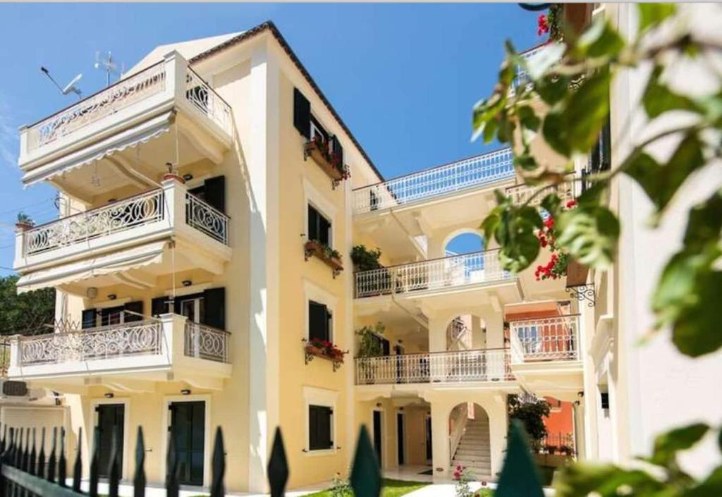 un gran edificio blanco con balcones. en Filoxenia Kirki Apartments by CorfuEscapes en Benitses