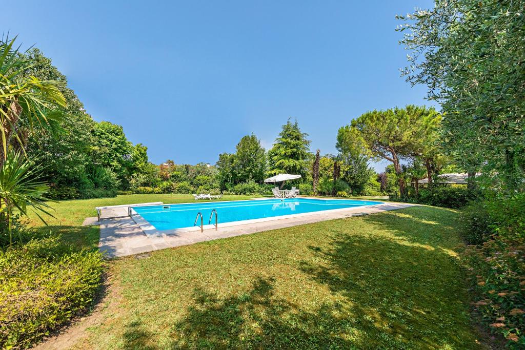 a large swimming pool in a yard with trees at Villa Lidia con piscina by Wonderful Italy in Moniga