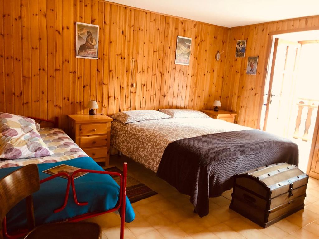 sypialnia z drewnianymi ścianami, łóżkiem i krzesłem w obiekcie CASA VACANZE NORA w mieście Chamois