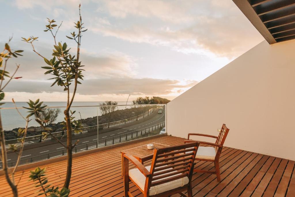 a wooden deck with a bench and a view of the ocean at Ocean View by Azores Villas in Ponta Delgada