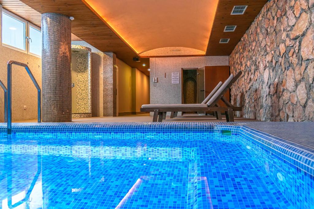a swimming pool in a hotel with a chair next to it at Hotel & Spa Tino Sveti Stefan in Ohrid