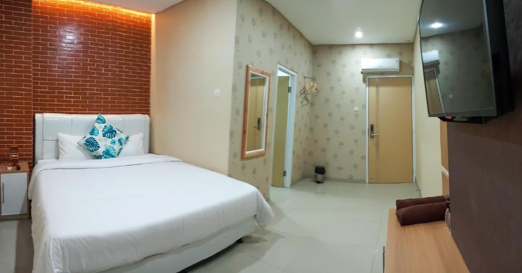 sypialnia z białym łóżkiem i telewizorem w obiekcie HOTEL LENGKONG 2 w mieście Bandung