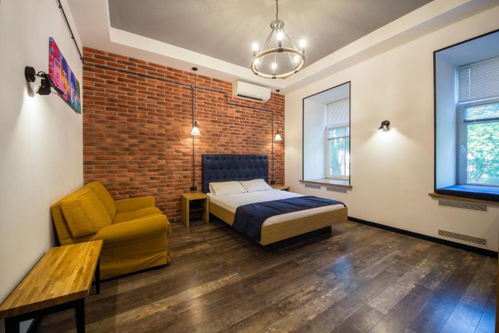 een slaapkamer met een bed en een stoel en een bakstenen muur bij Loft Design Apartments on Desyatynnyi Ln, 7 in Kiev