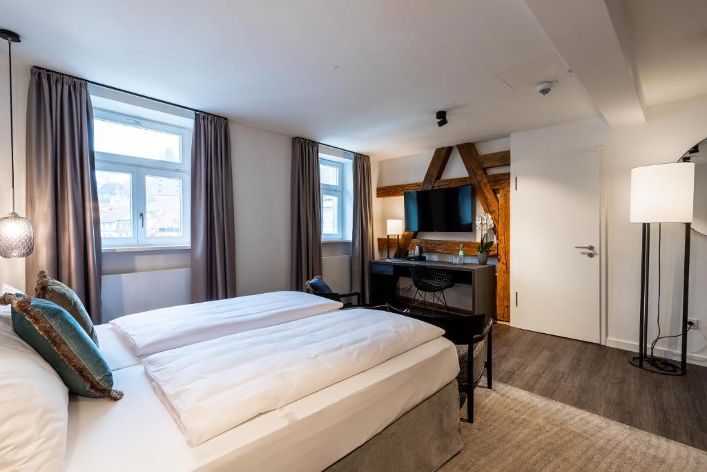 una camera d'albergo con un grande letto e una scrivania di Hotel Weißes Ross a Kulmbach