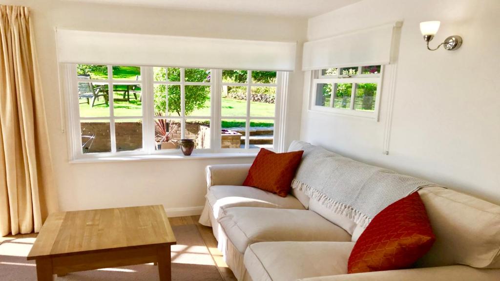 un soggiorno con divano, tavolo e finestre di Secret Chalet a Newton Poppleford