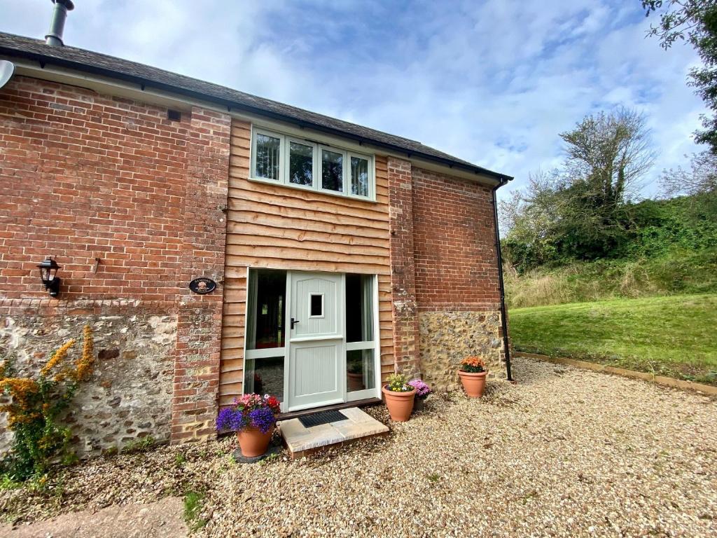 a brick house with a white door and potted plants at Bamford Barn in Ottery Saint Mary