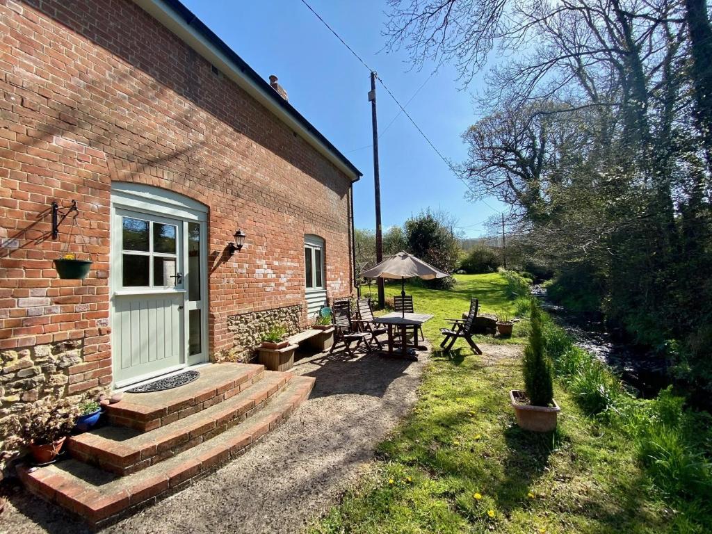 a brick house with a patio and a table and chairs at The Teddy House in Ottery Saint Mary