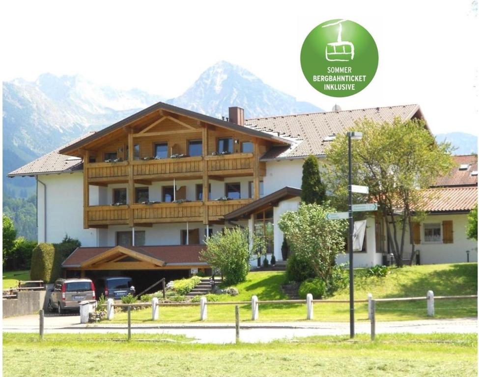 a large house with mountains in the background at Hotel AlpIn Bed & Breakfast in Fischen