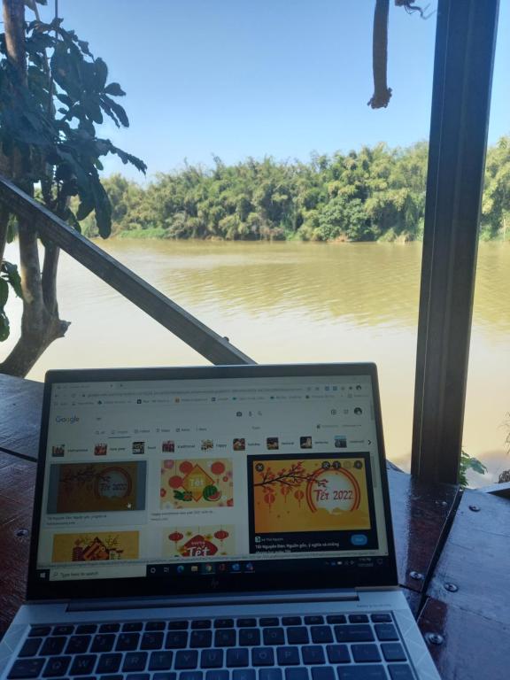 Tân PhúにあるLittlefarm - Nam Cat Tienの川前のテーブルに座ったラップトップ