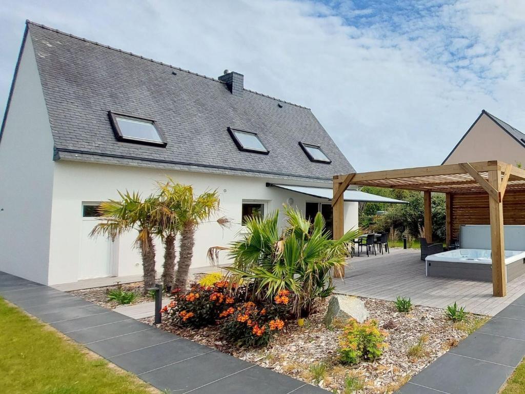 a white house with a patio and a wooden pergola at Cottage in Plouarzel in Plouarzel