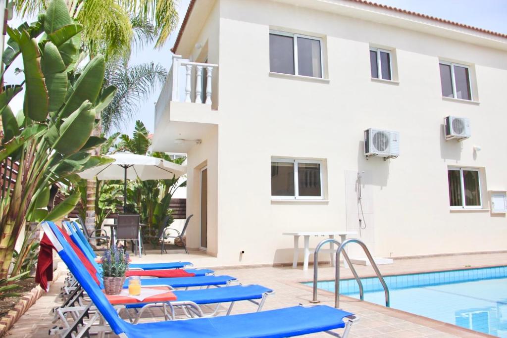 a row of blue lounge chairs next to a swimming pool at Villa Agnes in Ayia Napa