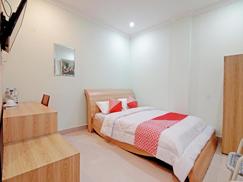 - une chambre avec un lit doté d'oreillers rouges et blancs dans l'établissement OYO 90857 Baaraka Syariah Hotel, à Pekanbaru