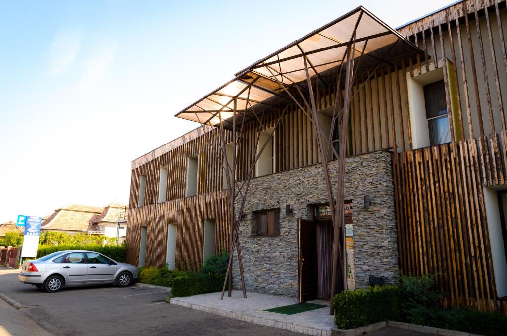 a building with a car parked in front of it at Pensiunea La Broscuta in Cîmpia Turzii