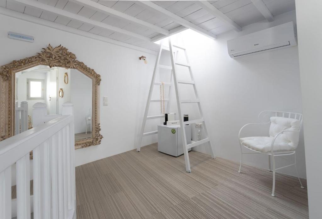 Jest to biały pokój z lustrem i krzesłem. w obiekcie aníko suites Chora w mieście Mykonos