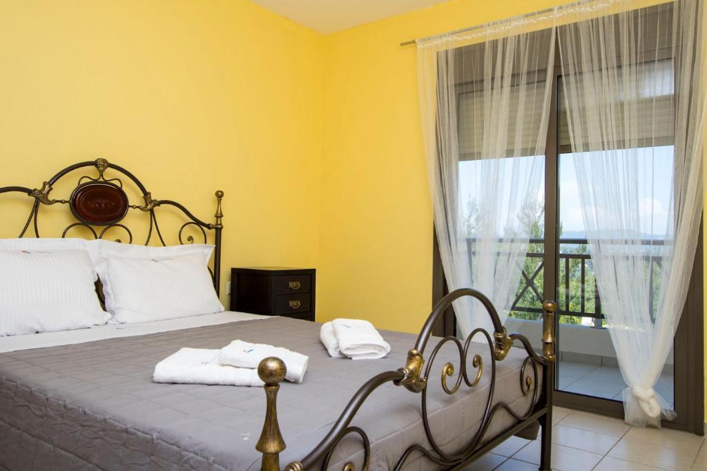 a bedroom with a bed with yellow walls and a window at Possidi Villas by Halkidiki Villas in Possidi
