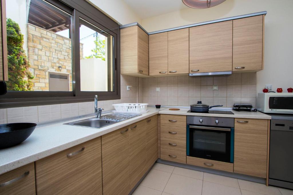 a kitchen with wooden cabinets and a sink and a window at Possidi Villas by Halkidiki Villas in Possidi