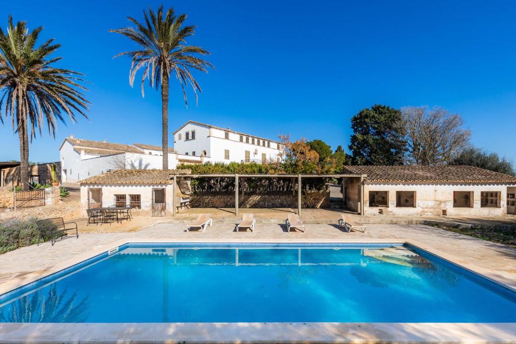 a swimming pool in front of a house with palm trees at Son Crespi Vell in Manacor