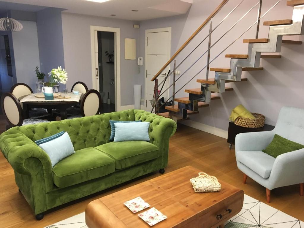 uma sala de estar com um sofá verde e escadas em Bournacell 16 em Cambados