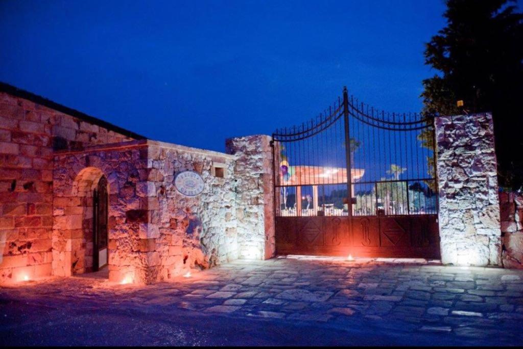 a stone building with a gate at night at Tenuta Le Casette in Ugento