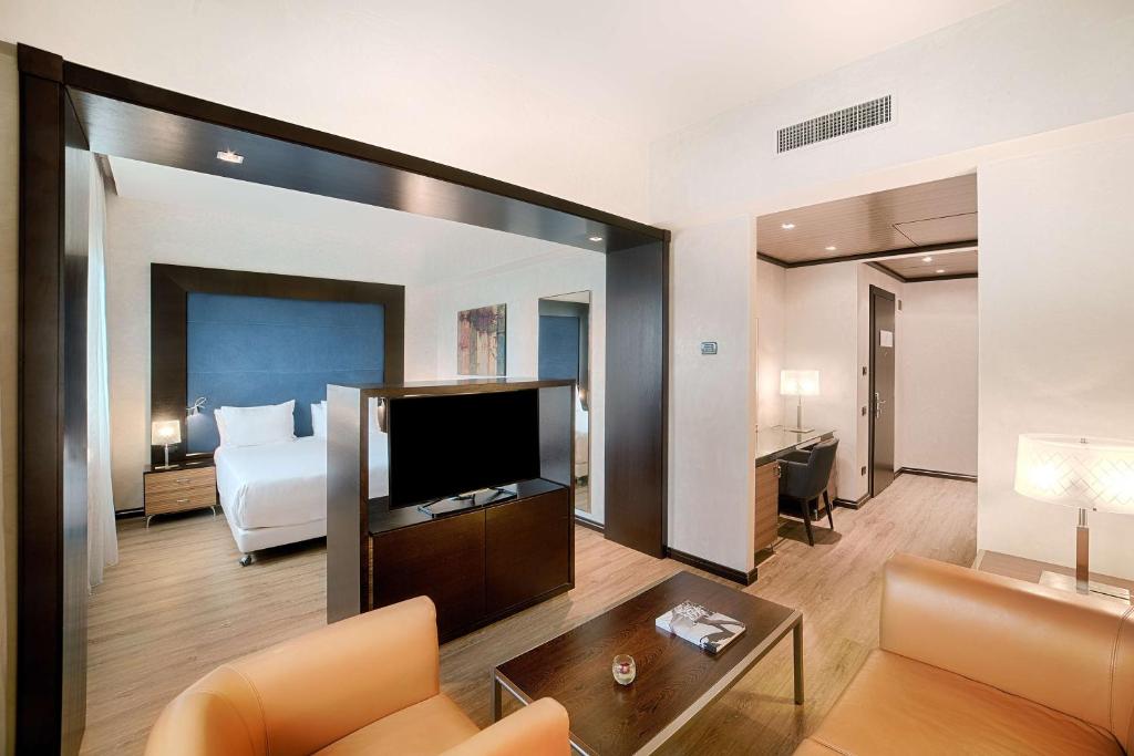 Habitación de hotel con cama y espejo grande en NH Siena en Siena