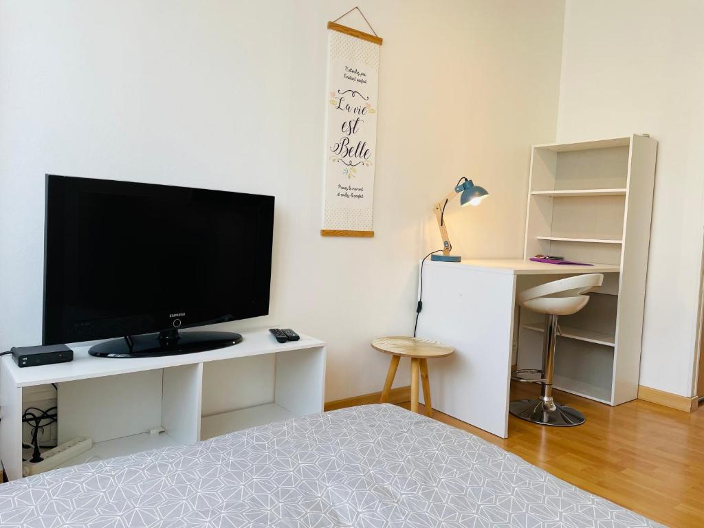 - un salon avec une télévision et un bureau avec un lit dans l'établissement Studio avec la fibre et jardin, au coeur de Lorient, à Lorient