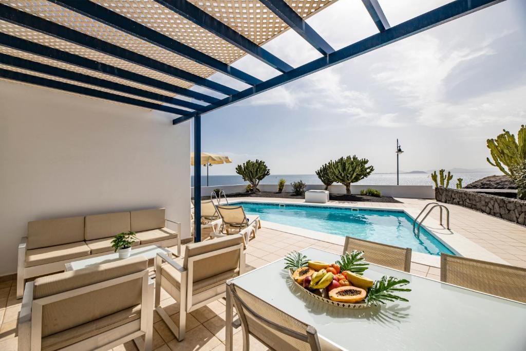 a villa with a swimming pool with a table and chairs at Lanzarote Villa The One in Playa Blanca