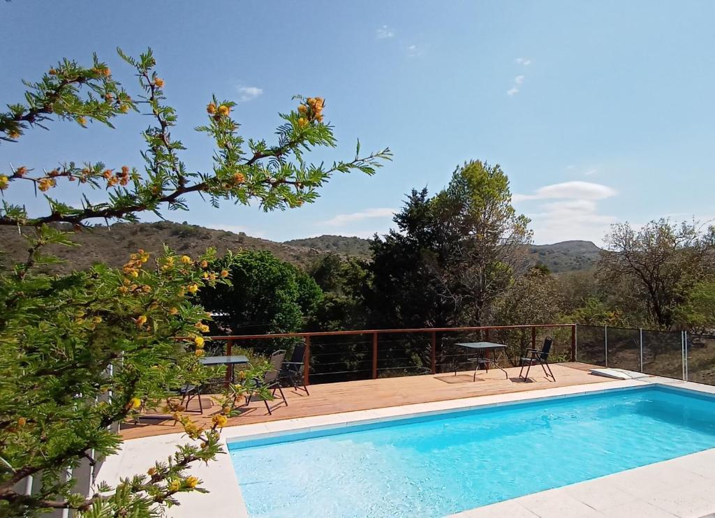 a swimming pool with chairs and tables on a deck at Cuesta los Robles -Casas Serranas- in Villa Icho Cruz