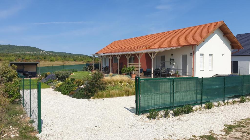 una casa en la playa con una valla delante en Búzavirág Apartmanház, en Balatonakali