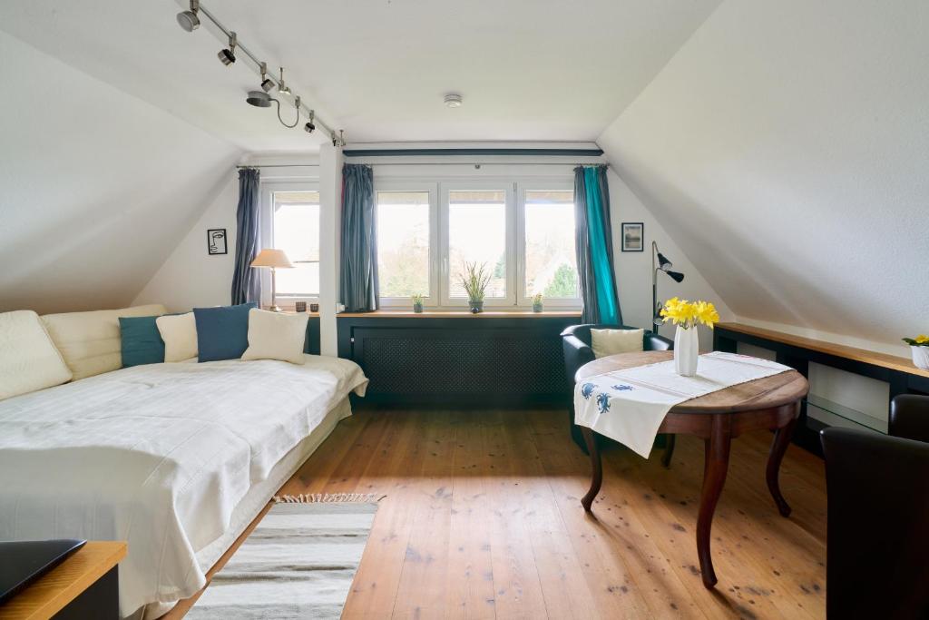 Schlafzimmer mit einem Bett, einem Tisch und Fenstern in der Unterkunft Ferienwohnung Ostseeperle Moba-Travel in Travemünde